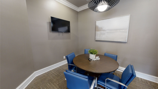 A five-person conference room with a round table and TV